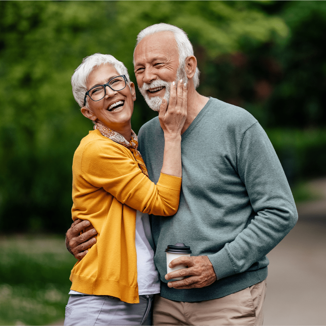 a man and woman smiling and holding a cup of coffee
